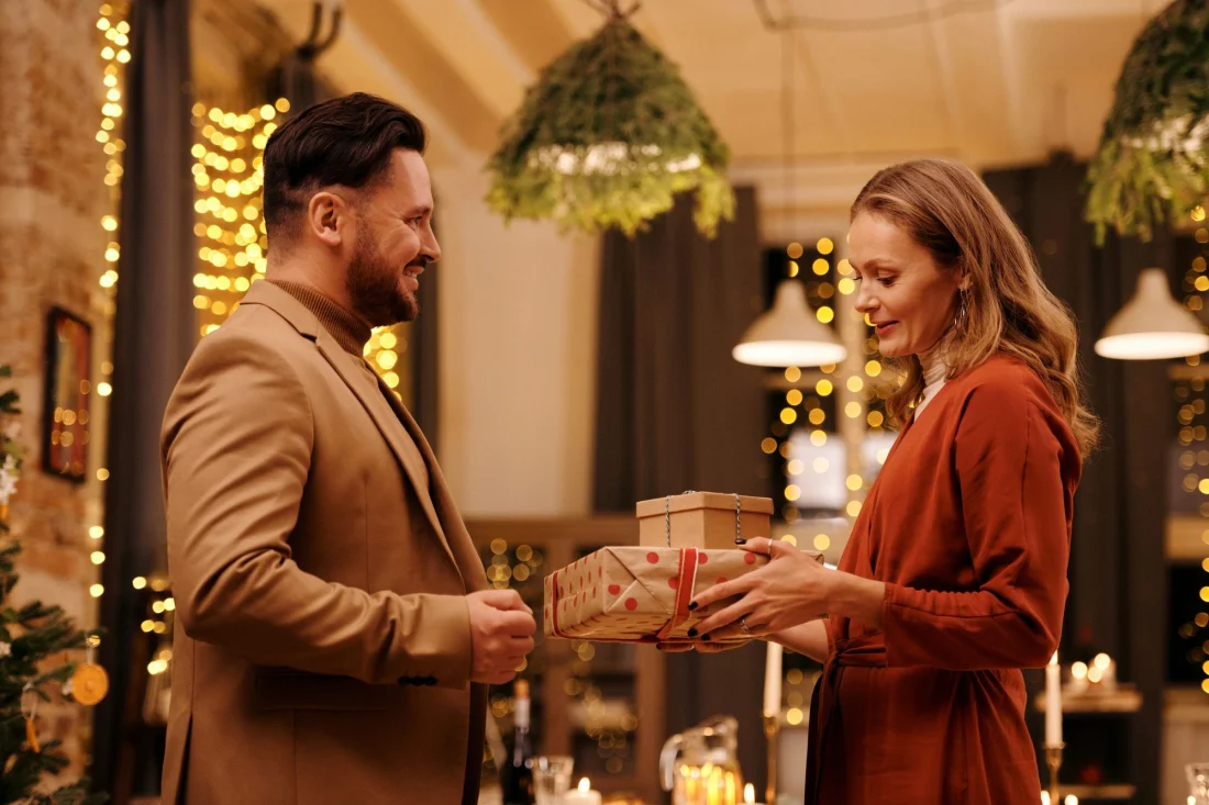 Eine Frau überreicht ihrem Mann zu Hause ein verpacktes Geschenk