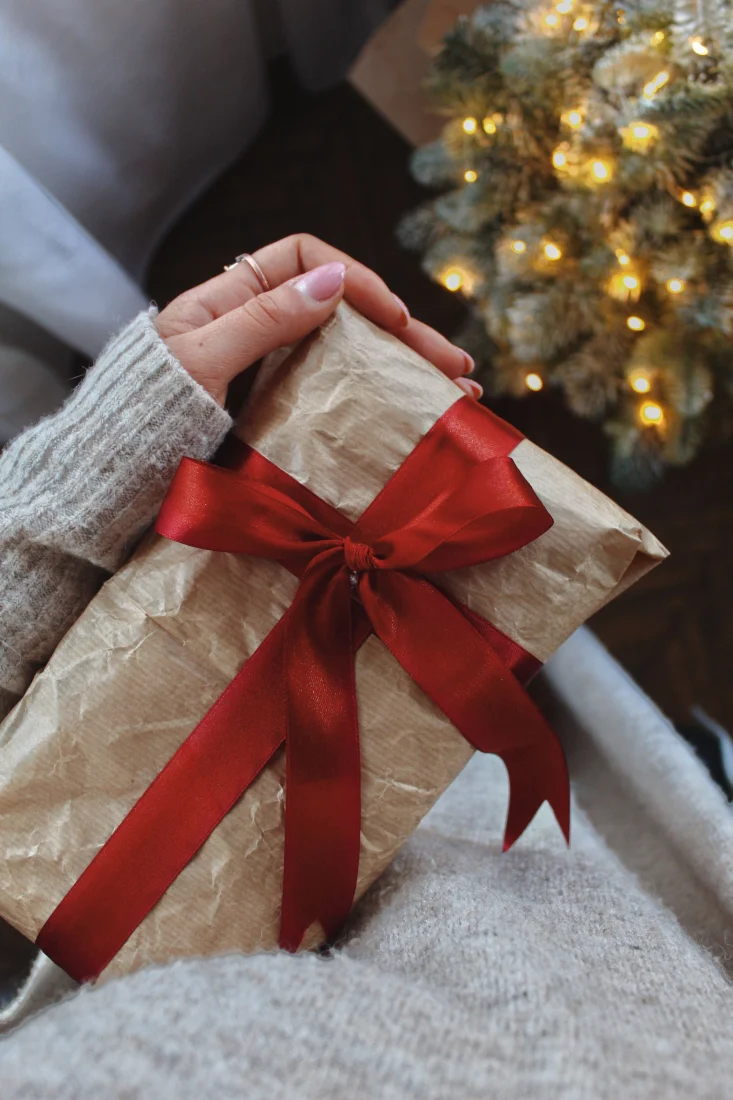 Eine Frau hält ein Geschenk mit roter Schleife